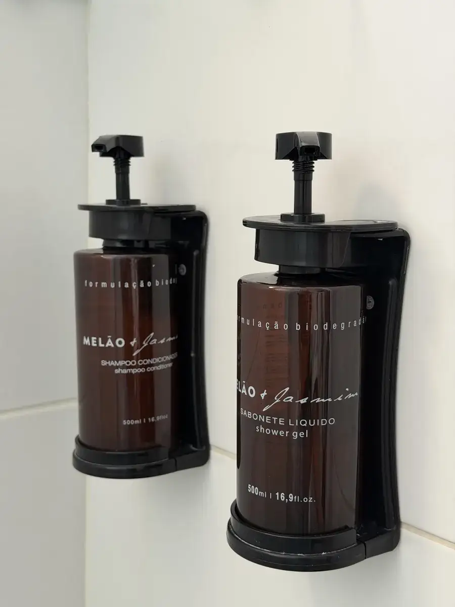 Dispensers de xampu e sabonete líquido Melão e Jasmim presos na parede do box
