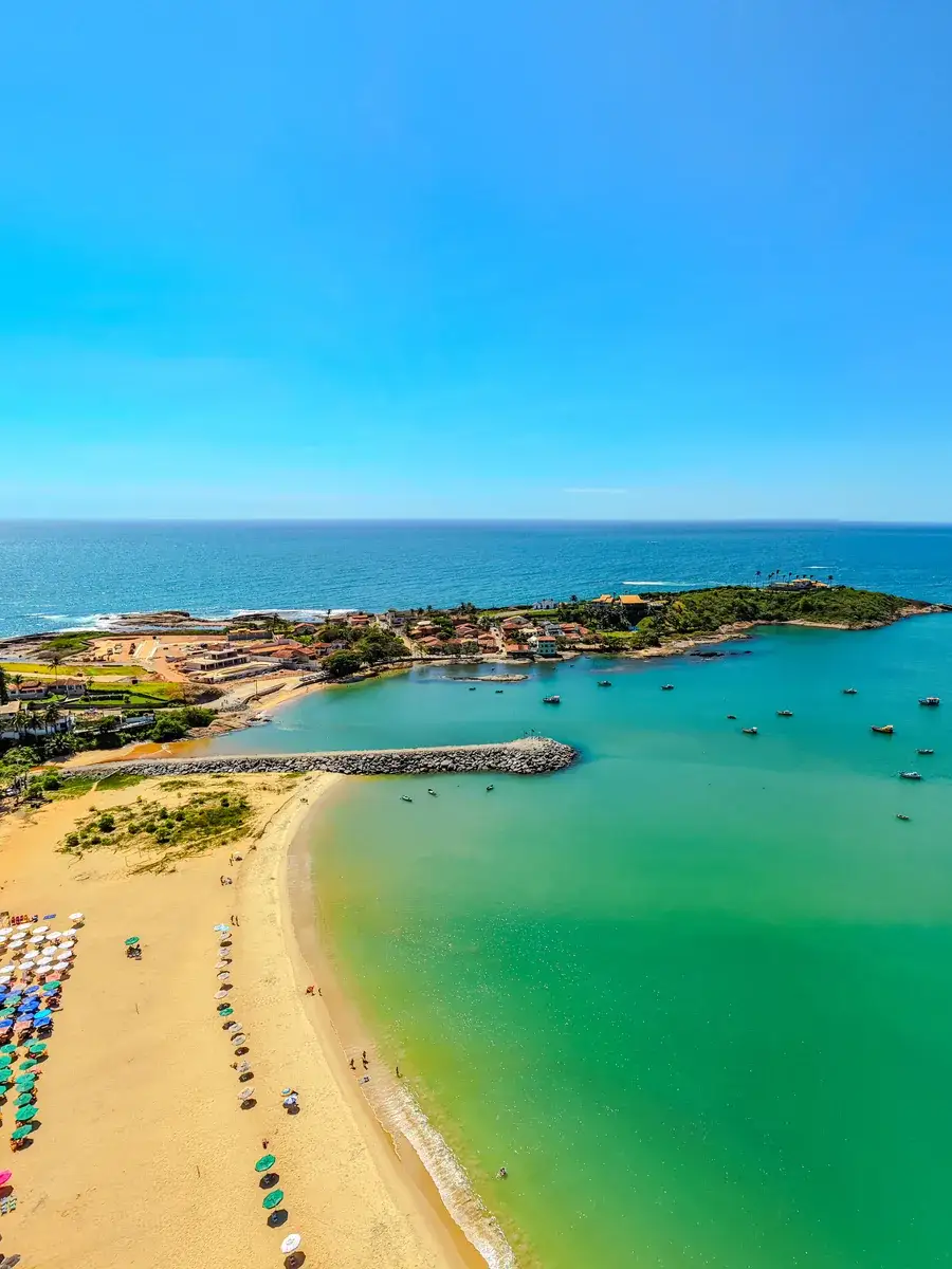 Vista aérea da enseada de Meaípe: a ponta rochosa, os barcos ancorados e a faixa de guarda-sóis na areia
