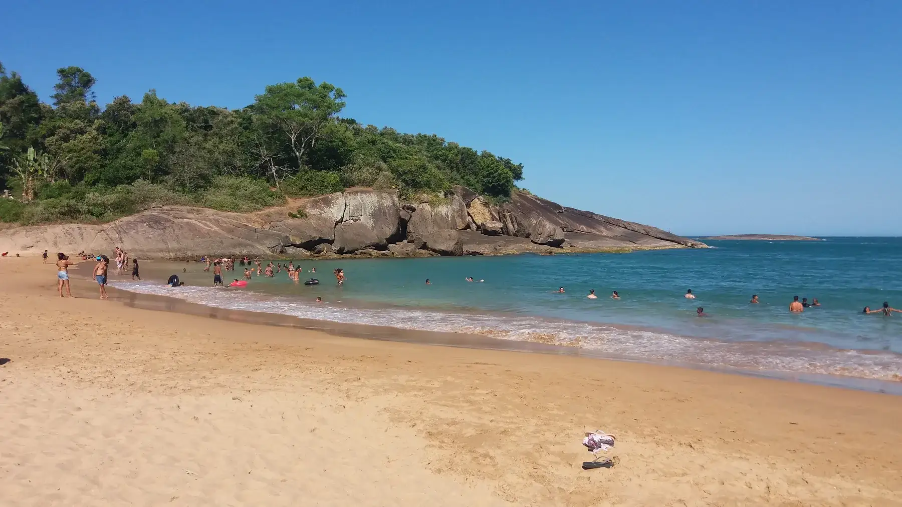 Enseada da Praia dos Padres com banhistas na água e o costão coberto de mata